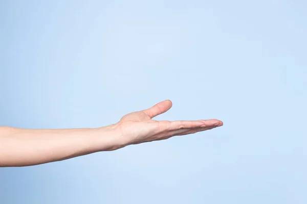 Handbewegung der Frau. Weibliche offene Hand auf hellblauem Hintergrund. Leere Handflächen in Pose, als hätte man etwas in der Hand. Frontansicht — Stockfoto