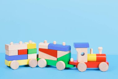 Renkli bloklu tahta oyuncak tren iyon açık mavi arka plan. Ön görünüm