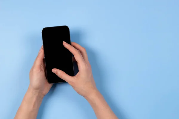 Kobieca ręka dotykająca ekranu wyświetlacza smartfona, za pomocą aplikacji, przeglądanie Internetu, zakupy online, jasnoniebieskie tło z miejsca na tekst — Zdjęcie stockowe