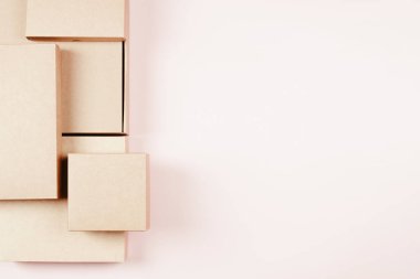 Pastel pembe arka planda farklı boyutlarda kahverengi karton kutular. Model yap. Üst görünüm