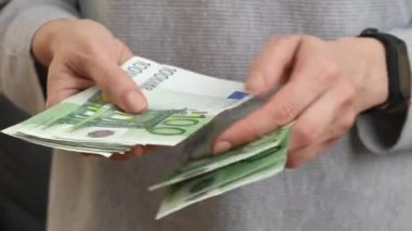 Kadın elleri Euro banknotlarını sayıyor, elini uzatıyor, birine para sayıyor, para ödüyor. Nakit ödeme, gelir, aile bütçesi, yatırım, rüşvet. 100 Euro 'luk banknotlar kadınların elinde. 4k görüntü