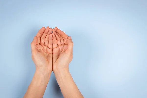 Empty cupped palm hands, keeping hands together on light blue background. Top view to outstretched woman hands. Care, help, support, charity, donation concept — Stockfoto