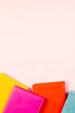 Pastel pembe arka plan üzerine renkli ciltli kitaplar. Eğitim, kendi kendini öğrenme, kitap değiştirme, kitap değiştirme konsepti. Üst görünüm, metin için boşluk kopyala