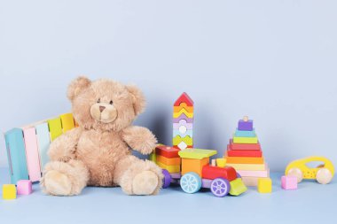 Eğitimli çocuklar oyuncak koleksiyonu. Oyuncak ayı, tahta tren, gökkuşağı rengi ksilofon ve açık mavi arka planda bebek oyuncakları. Sürdürülebilir, çevre dostu oyuncaklar. Ön görünüm