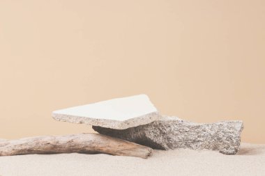 Grunge beton taşları ve beyaz kumsal arka planında kuru ağaç dalları. Kozmetik veya ürün sunumu için en az yaratıcı kompozisyon. Ön görünüm