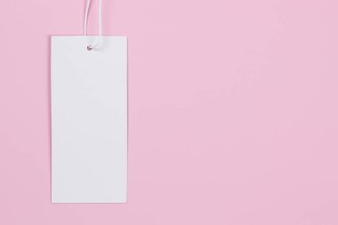 Pastel pembe arka planda boş beyaz dikdörtgen etiket. Fiyat etiketi maketi. Üst görünüm, alanı kopyala