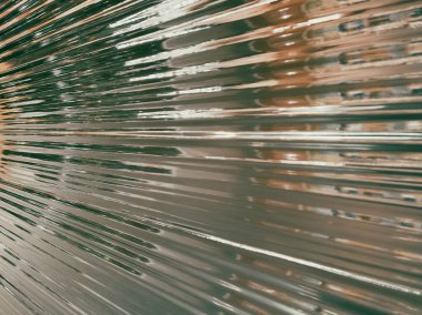 Plastik ambalaj arka planı. Buruşmuş plastik selofan kırışıklığı. Plastik yüzeydeki kıvrımlara ve kıvrımlara ışığı ve gölgeyi yansıtıyor. Doku kaplama efekti şablonu.