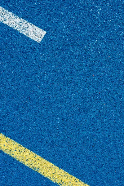 Colorful sports court background. Top view blue field rubber ground with white and yellow lines outdoors