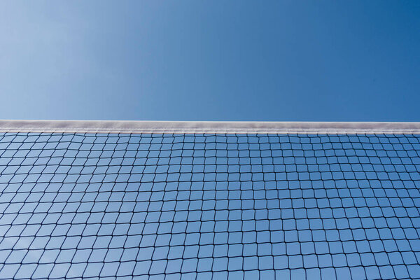Tennis or volleyball net against clear blue sky background. Outdoors sports field in sunny day.