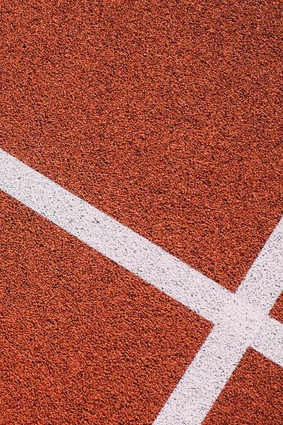 Colorful sports court background. Top view to red field rubber ground with white lines outdoors