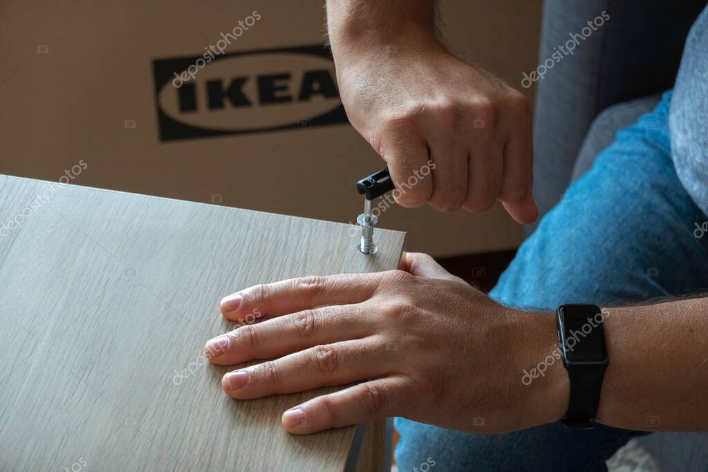 Vilnius, Lithuania - July 7, 2022: Man hands assembling Ikea furniture using screw allen. IKEA is Swedish-founded, worlds largest furniture retailer.