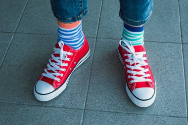 Farklı çorap giyen bir çocuk. Gri arka planda uyumsuz çoraplar içinde çocuk bacakları. Tuhaf Çorap Günü, Zorbalık Karşıtı Hafta. Down sendromu farkındalık kavramı.