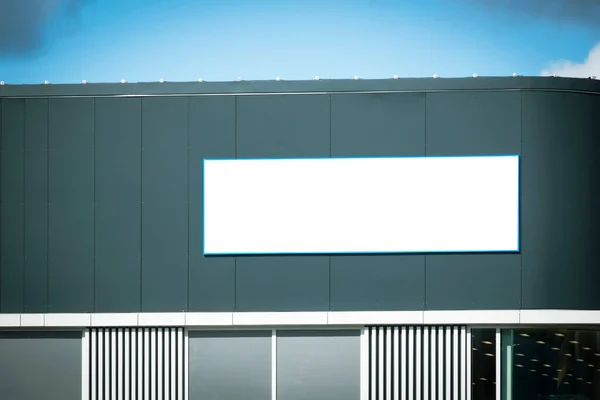 Mock up template. Big horizontal white blank signboard, advertising billboard on modern building wall outdoors.