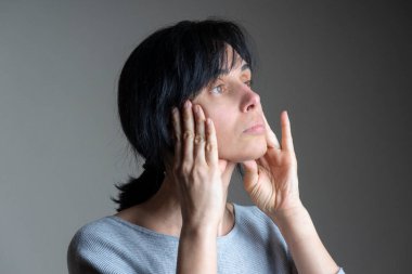 Yüz yogası, yüz jimnastiği, günlük kişisel bakım. Orta yaşlı beyaz kadın evde yüz egzersizi yapıyor..