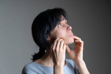 Yüz yogası, yüz jimnastiği, günlük kişisel bakım. Orta yaşlı beyaz kadın evde yüz egzersizi yapıyor..