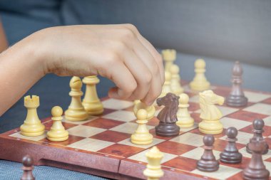 Evde satranç oynarken satranç figürünü tutan çocukların yakın çekimi. Eğitim, stratejik masa oyunu, boş zaman, evde eğlence.