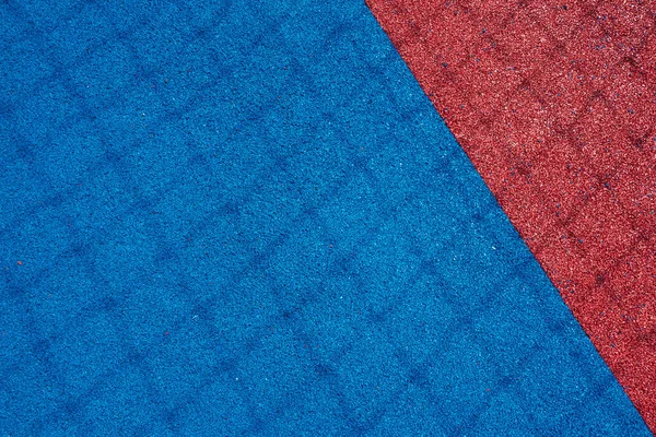 Colorful sports court background. Top view light blue and red field rubber ground with shadow from football goal net in sunny day outdoors.