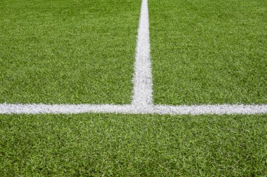 Beyaz çizgili yeşil sentetik çimen futbol sahası.