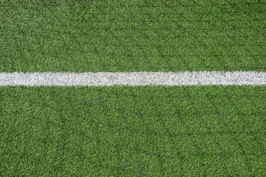 Yeşil sentetik çimen futbol sahası ya da beyaz çizgili futbol sahası ve güneşli bir günde futbol kalesinin gölgesi..