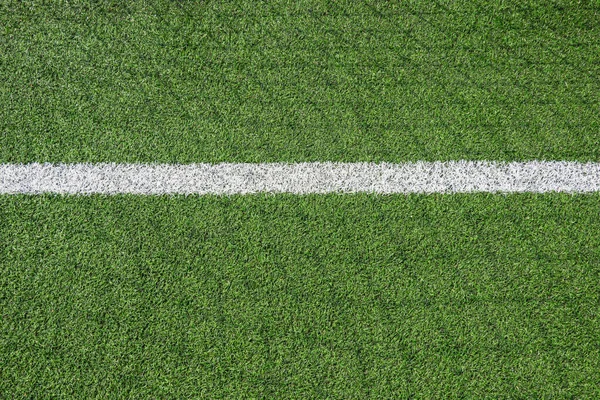 Green synthetic artificial grass football or soccer field with white line and shadow from football goal net in sunny day outdoors.