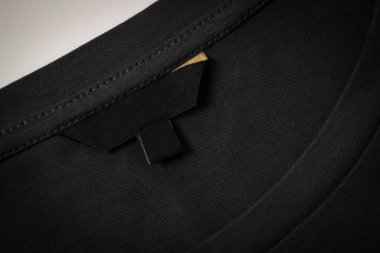 Siyah kumaş arkaplanda siyah boş kıyafet etiketi. Üst görünüm.