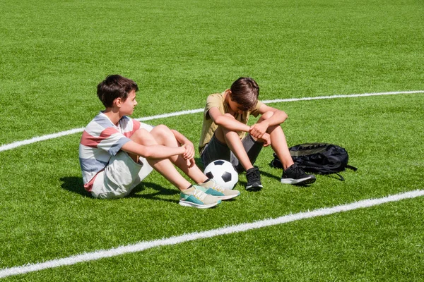 Teenage boy comforting consoling upset sad friend in school stadium. Education, bullying, conflict, social relations, problems at school, learning difficulties concept.