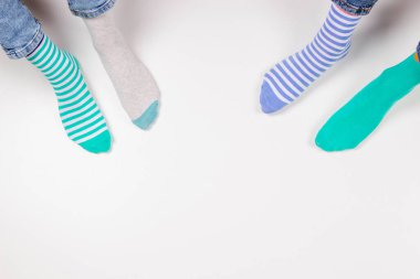 Farklı çorap giyen bir çocuk. Beyaz arka planda oturan uyumsuz çorapların içinde çocuk ayakları. Çorap Günü, Zorbalık Karşıtı Hafta, Down Sendromu Farkındalık Konsepti.