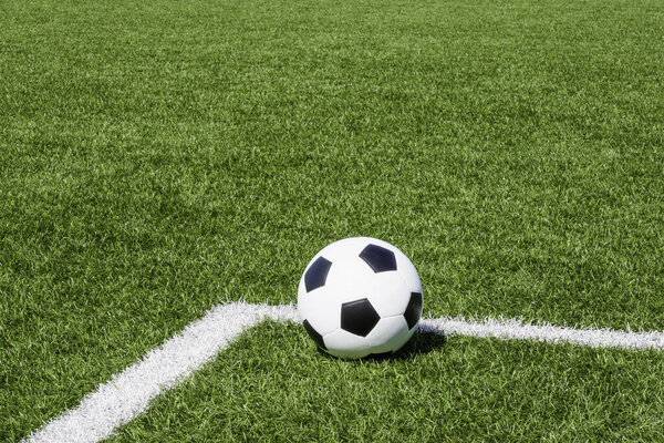 Soccer ball on green synthetic artificial grass soccer sports field with white corner stripe line.