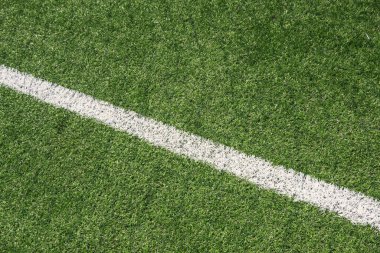 Green synthetic artificial grass soccer sports field with white line.