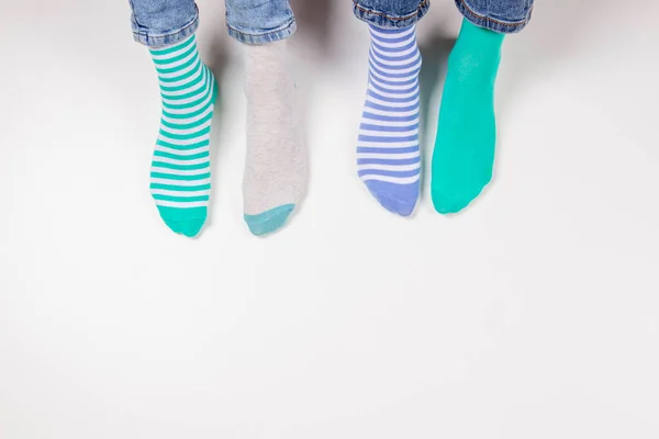 Children wearing different pair of socks. Top view to kids foots in mismatched socks sitting on white background. Odd Socks day, Anti-Bullying Week, Down syndrome awareness concept.