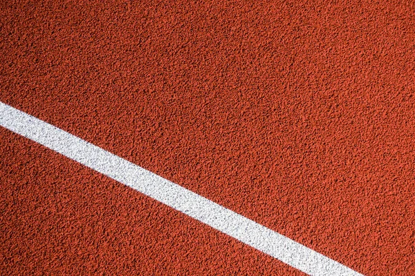 Colorful sports court background. Top view to red field rubber ground with one white line outdoors.