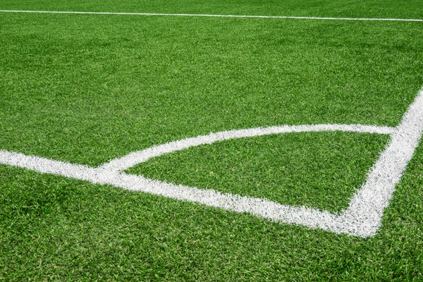 Green synthetic artificial grass soccer sports field with white corner stripe line.