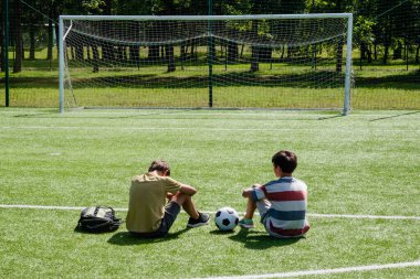 Teenage boys talking in school stadium outdoors. Teenage boy comforting consoling upset sad friend. Education, bullying, conflict, problems at school, lost game, learning difficulties, empathy concept