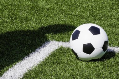 Futbol sporu geçmişi. Futbol topu ve oyuncunun gölgesi güneşli bir günde suni saha futbol sahasında..