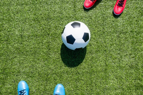 Soccer football background. Soccer ball and two players standing on artificial turf soccer field with shadow from football goal net on sunny day outdoors. Top view.