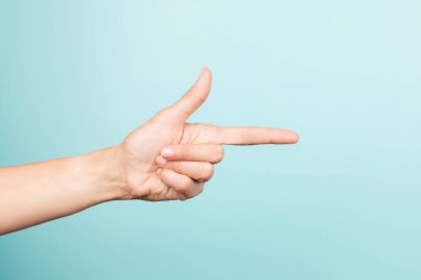 Woman hand gesture. Female hand points finger at something on light blue background. Front view
