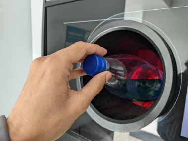 Otomatı ters çevir. Kadın eli boş plastik şişeyi makineye koydu. Metal içki kutuları, plastik ve cam şişeler için geri ödeme ve geri dönüşüm otomatı.