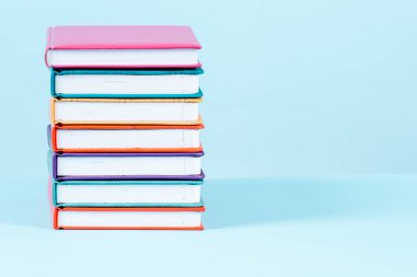 Açık mavi arkaplan üzerine bir yığın kitap. Ön görünüm, metin ya da ürün alanı kopyala. Eğitim, okula dönüş konsepti..
