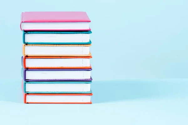 Stack of books on light blue background. Front view, copy space fot text or product. Education, back to school concept.