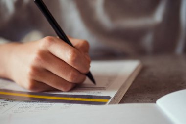 Okuma güçlüğü çeken bir çocuk ödev yapıyor, yazıyor, renkli kaplama şerit kullanarak not defteri okuyor. Eğitim, öğrenme güçlüğü, okuma güçlüğü konsepti.