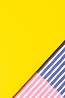 Soyut geometrik moda renkli kağıt doku arka planı. Kırmızı, mavi, beyaz çizgili çizgili ve metin için fotokopi alanı olan boş sarı kağıtlı arkaplan. Üst manzara, düz uzanma.