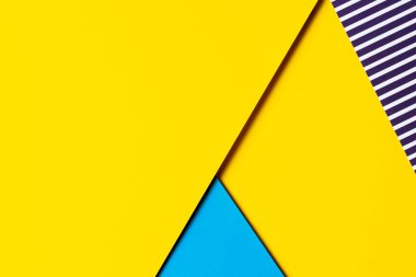 Soyut geometrik parlak renkli kağıtların doku arka planı. Sarı arka plan ve mavi, arasında mavi ve beyaz çizgiler olan çizgili kağıt. Üst manzara, düz uzanma.