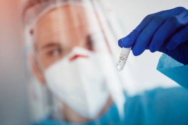 Kadın doktor elinde kovid 19 koronavirüs aşısı olan bir tüp tutuyor. 
