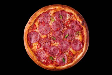 Siyah arka planda salamlı ve biberli pizza.