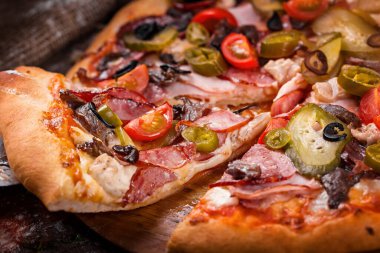 Salamlı pizza sosis, jambon, çan biberi ahşap tahtaya serpiştirilmiş un.