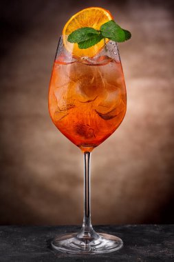 Aperol spritz cocktail served in a wine glass decorated with orange chips and mint sprig clipart
