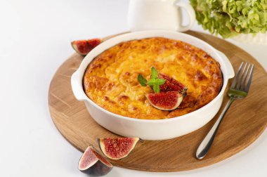 Tahta bir tahtanın üzerinde yuvarlak beyaz şekilli balkabağı güveci incirle süslenmiş beyaz masa, servis edilen restoran.