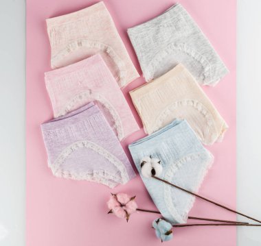 Pamuk gibi rahat külotlar pembe arka planda katlanmış pastel renkler, üst manzara.