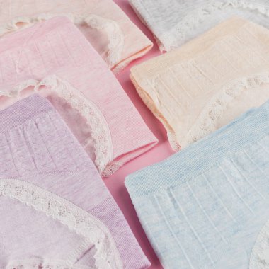 Pamuk gibi rahat külotlar, pembe arka planda katlanmış pastel renkler, yakın plan.