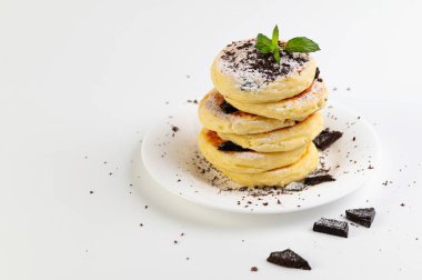 süzme peynir krepleri, beyaz bir tatlı tabağında krep ve beyaz arka planda nane şekeri.